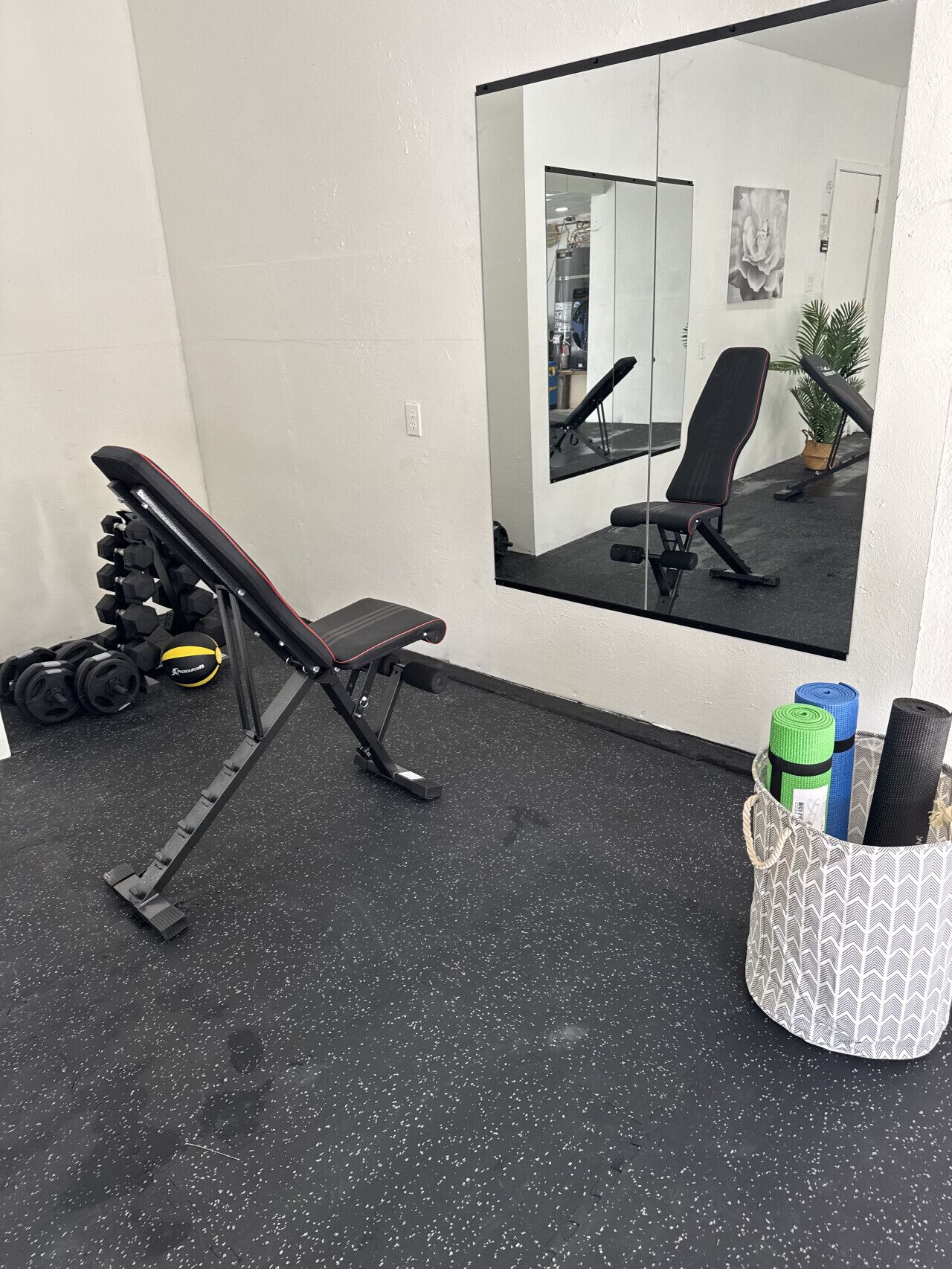 Une salle de sport équipée d’un banc, d’haltères et d’un support pour tapis de yoga.