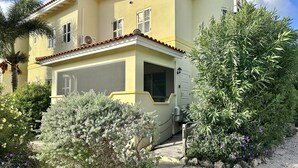 A two-story building with a yellow facade, a covered porch, and a gravel driveway.
