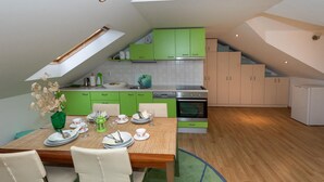 A compact kitchen with green cabinets, a dining table set for four, and a small oven. - 2 bedroom gorgeous home in Blace (Blace)