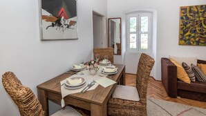 A dining area with a wooden table set for four, surrounded by wicker chairs. - 2 bedroom gorgeous home in Blace (Blace)