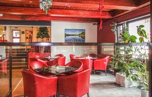 A restaurant with red chairs and tables, a Christmas tree, and a painting of a lake. - Lovely apartment in Goslar with WiFi (Goslar)