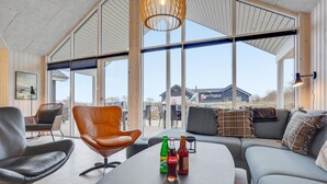 A modern interior with a large window, a leather chair, a sofa, and a table with drinks. - Gorgeous home in Sydals with sauna (Sydals)