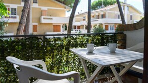Ein Balkon mit Tisch und zwei Stühlen, mit Blick auf eine Reihe gelber Häuser mit Balkonen.