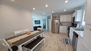 Una cocina moderna con armarios blancos, un refrigerador de acero inoxidable y un horno empotrado.