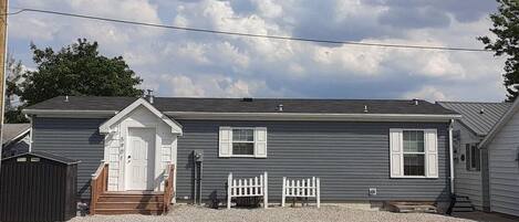 A two-story house with a front porch, a small attached garage, and a gravel driveway.