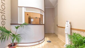 Un área de recepción con un mostrador curvo, un dispensador de agua y plantas en macetas.