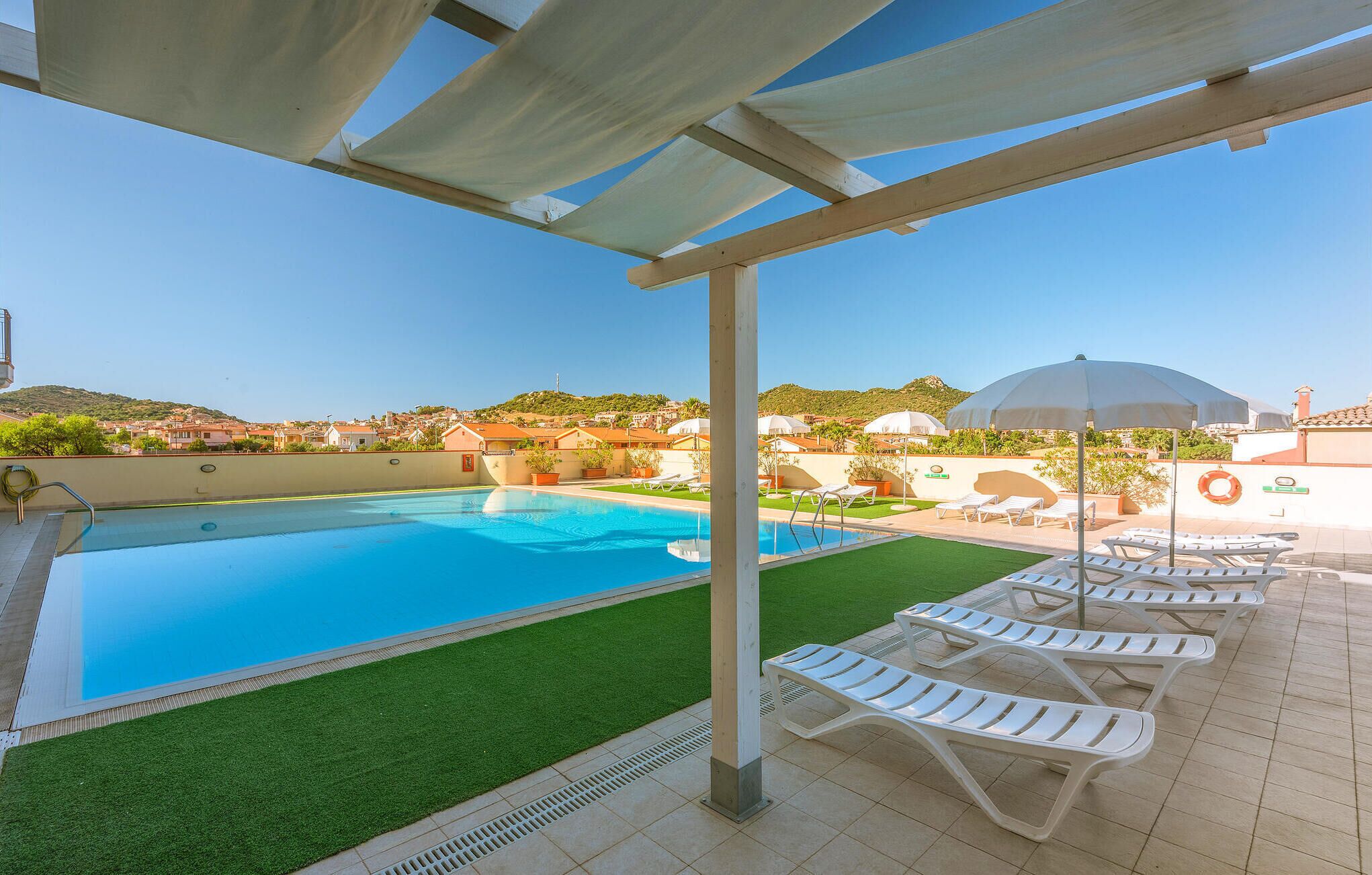 Un área de piscina en la azotea con vistas despejadas de los edificios y colinas circundantes.