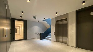 A modern hallway with a staircase leading to an elevator.