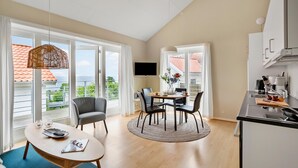 A modern kitchen with a dining area, large windows, and a view of the sea. - 2 bedroom gorgeous home in Gudhjem (Gudhjem)