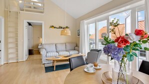 A spacious living area with a sofa, dining table, and a view of the outside. - 2 bedroom gorgeous home in Gudhjem (Gudhjem)