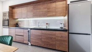 A modern kitchen with wooden cabinets, a stainless steel refrigerator, and built-in appliances.
