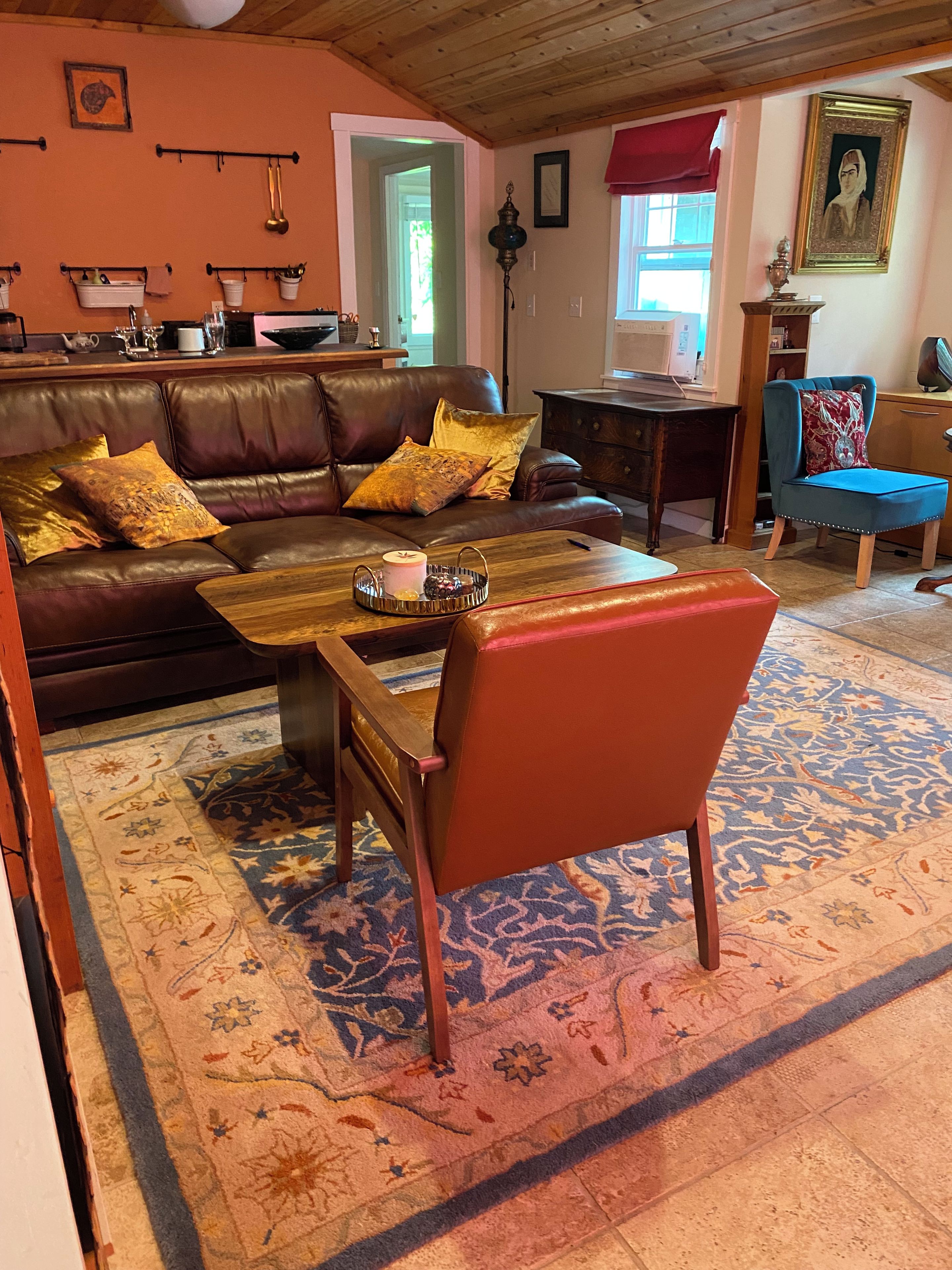 Un salon chaleureux avec un canapé en cuir marron, une table basse en bois et un tapis à motifs.