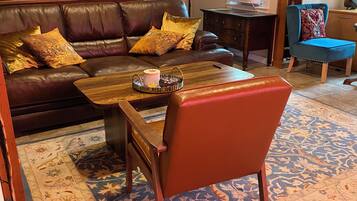 Un salon chaleureux avec un canapé en cuir marron, une table basse en bois et un tapis à motifs.
