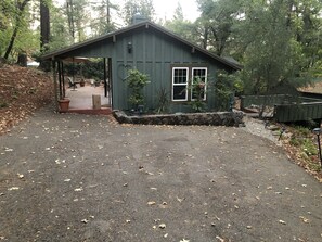 A small, green wooden building with a covered entrance and a stone wall in front. - Cozy cottage in woodsy haven - 2 miles from downtown Calistoga (Callistoga)