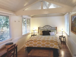 A bedroom with a bed, two bedside tables, a chair, and a window with blinds. - Cozy cottage in woodsy haven - 2 miles from downtown Calistoga (Callistoga)