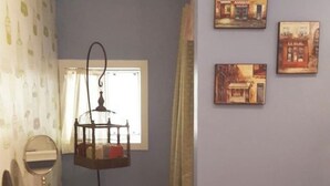 Un baño con tocador rojo, una lámpara colgante y tres cuadros en la pared.