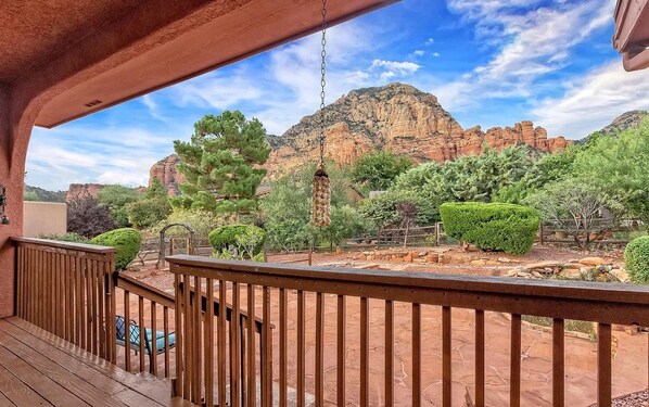 A wooden deck with a view of red rock formations and greenery.