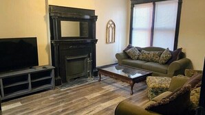 Un salon avec une cheminée, un téléviseur, un canapé et une table basse.