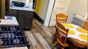 Une cuisine équipée d’une cuisinière à gaz, de meubles de rangement en bois et d’une table à manger avec des chaises.