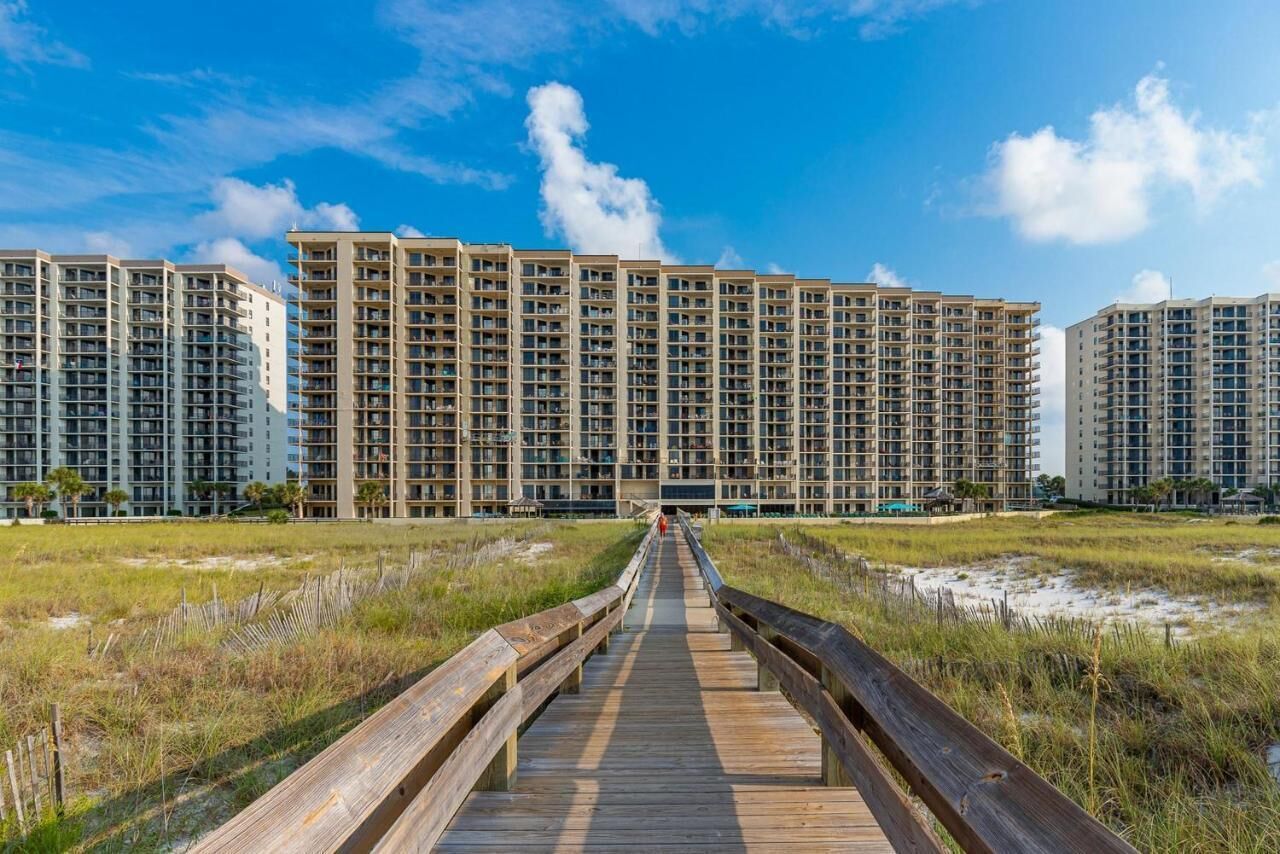 A boardwalk leading to high-rise buildings with multiple floors and balconies.