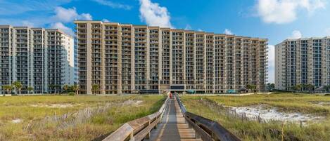 A boardwalk leading to high-rise buildings with multiple floors and balconies.