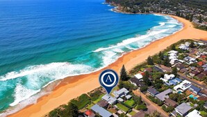 Vue aérienne d’une zone côtière avec une plage, l’océan et des immeubles résidentiels.