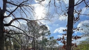 A deck with four blue chairs, a barbecue grill, and a view of a lake. - Lakefront Chalet w/ Covered Boat Dock - Sleeps 8 - 1 Hour from Dallas (Malakoff)
