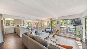 A spacious living area with a large sofa, a dining table, and a kitchen area. - Lakefront Chalet w/ Covered Boat Dock - Sleeps 8 - 1 Hour from Dallas (Malakoff)