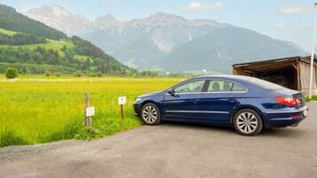 Ein blaues Auto auf einer Landstraße, mit Bergen im Hintergrund.