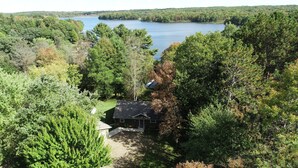 Talo, jonka ympärillä on tiheä metsä ja taustalla näkyy järvi.