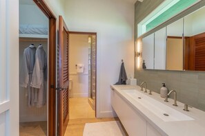 Un bagno moderno con un lungo piano lavabo, più lavandini e uno specchio grande.