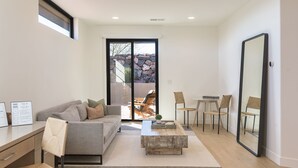 A modern living room with a grey sofa, wooden coffee table, and a dining area with chairs. - *New Owner Special* - Modern Luxury Casita (Ivins)