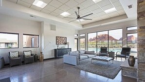 A spacious living room with a large window, a ceiling fan, and a stone accent wall. - *New Owner Special* - Modern Luxury Casita (Ivins)