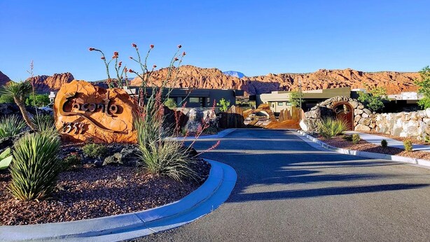 A desert resort entrance with a large rock sign, modern buildings, and a clear blue sky. - *New Owner Special* - Modern Luxury Casita (Ivins)