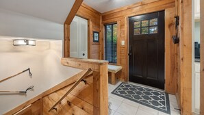 Interior de madera con un banco, una puerta y una lámpara.