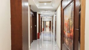 A hotel corridor with a polished floor, wooden doors, and a framed painting on the wall. - Wenzhou Lima Business Hotel (Binhai Industrial Park Branch, Wenzhou Longwan Airport) (Wenzhou)