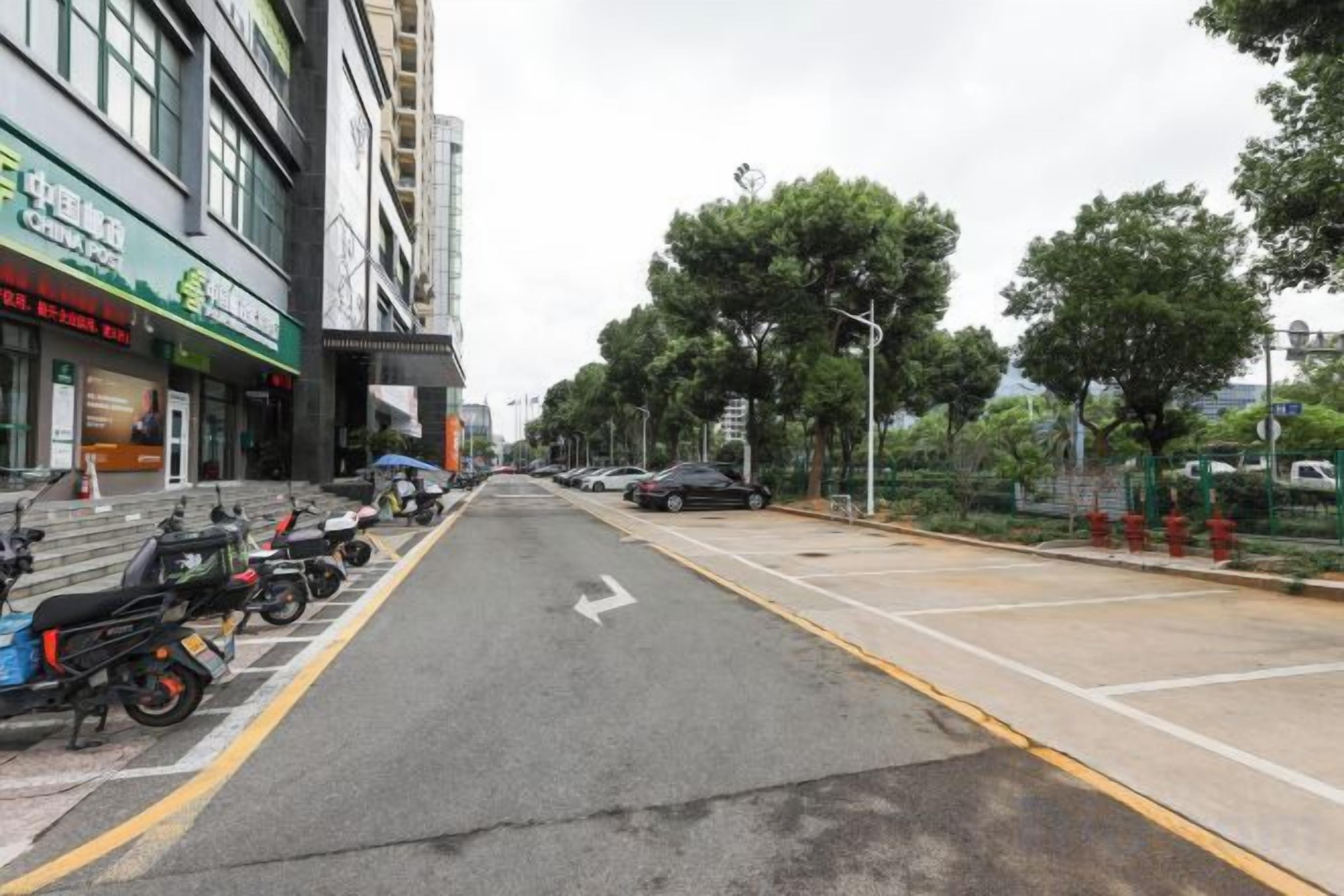 A street with parked motorcycles, a clear road, and buildings with signage.