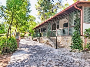 Ein gepflasterter Weg führt zu einem Gebäude mit einer Veranda und Steinmauern.