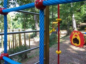 A playground with a rope climbing structure and a lion-shaped play area.