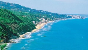 A coastal landscape with a beach, cliffs, and a clear blue sea.