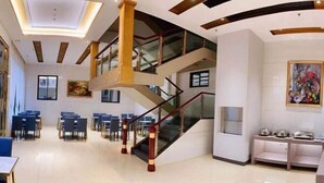 A spacious hotel lobby with a central staircase, multiple seating areas, and a dining setup. - Jinhao Business Hotel (Lufeng)