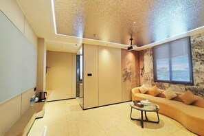 A modern living room with a sofa, a coffee table, and a decorative wall. - Jinhao Business Hotel (Lufeng)