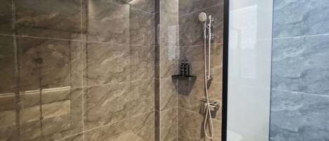 A modern bathroom with a glass-enclosed shower, marble tiles, and a toilet.