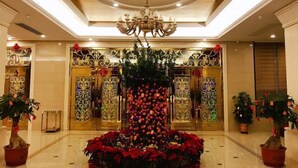 A lobby with a chandelier, decorative panels, and potted plants. - Jinhao Business Hotel (Lufeng)