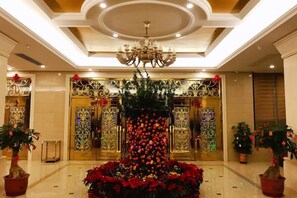 A hotel lobby with a chandelier, decorative floral arrangements, and ornate doors. - Jinhao Business Hotel (Lufeng)
