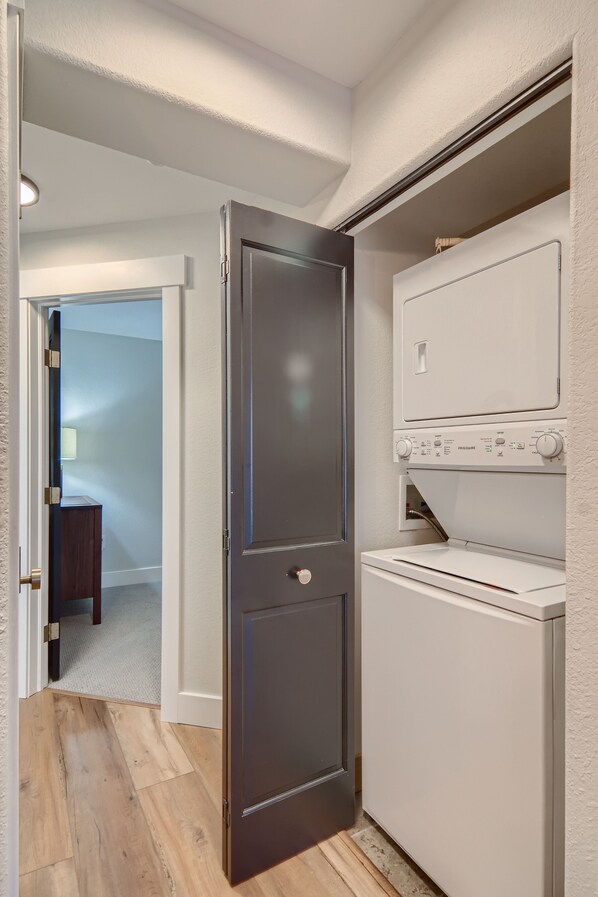 A laundry room with a dark door, a white washing machine, and a dryer. - Luxury Condo within walking distance to all the restaurants, shopping and bars. (Steamboat Springs)