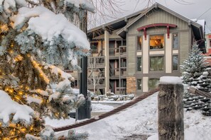 Un edifici d'edificis amb balcons, un paisatge cobert de neu i un arbre de Nadal amb llums.