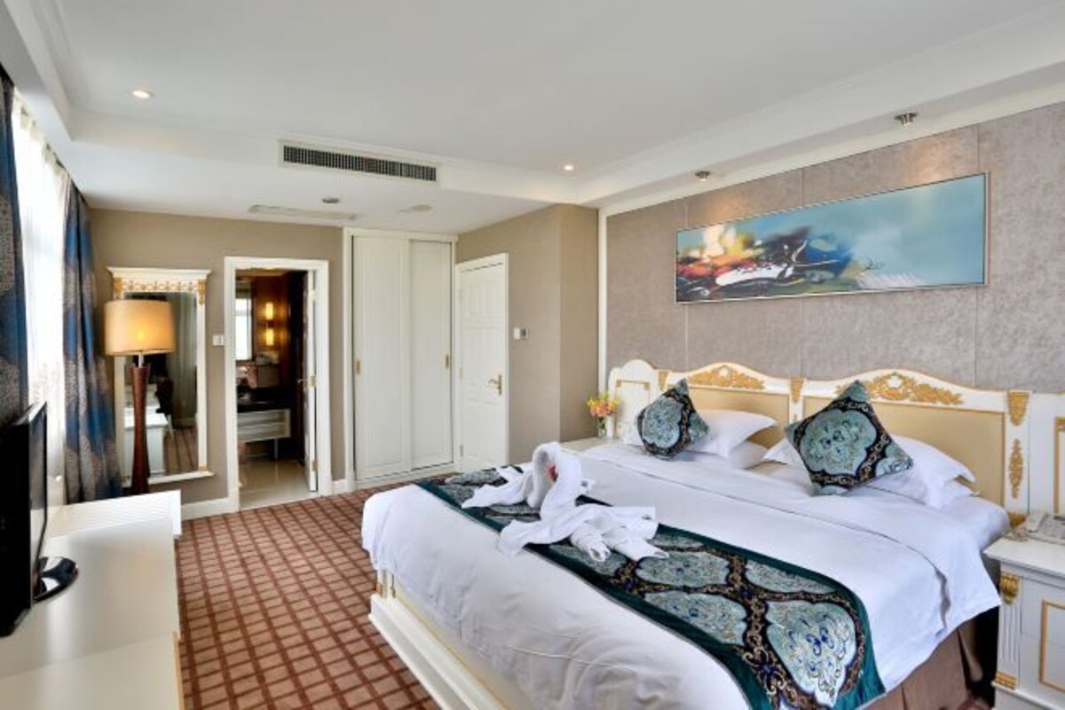 Ein Hotelzimmer mit einem großen Bett, einem Fernseher und einem Bild an der Wand.