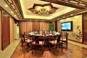 A conference room with a round table, chairs, a chandelier, a television, and decorative wall elements. - Zhong'an Huana Holiday Hotel (Hangzhou)