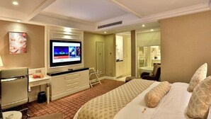 Ein Hotelzimmer mit Bett, Schreibtisch, Fernseher und einem durchgegangenen Tür sichtbaren Badezimmer.